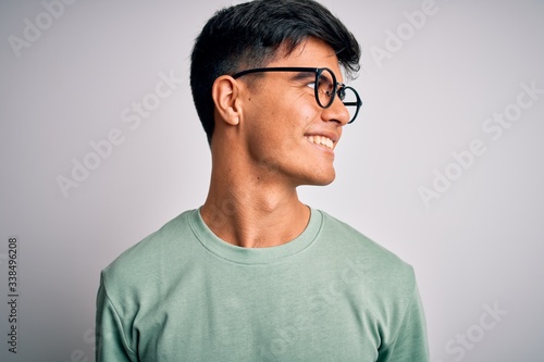 Young handsome man wearing casual t-shirt and glasses over isolated white background looking away to side with smile on face, natural expression. Laughing confident. © Krakenimages.com