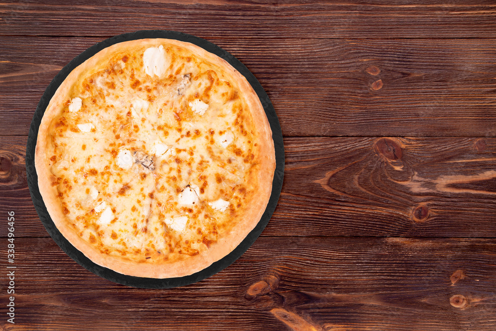 Pizza five cheeses on slate bottom, on wooden table, top view, space for text Pizza five cheeses on slate bottom, on wooden table, top view, space for text