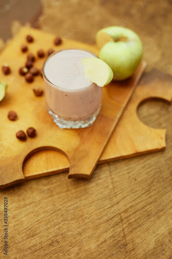 Yogurt with apple and nuts on a wooden background. Daylight.