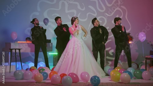 beauty bride in bridal veil and guests dancing in wedding .Beautiful model girl in a white wedding dress,multi-colored air balloons on the floor,room with decorated with colorful neon lights,