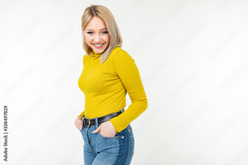 smiling cute girl in a lemon turtleneck and jeans flirts on an isolated white background with copy space smiling cute girl in a lemon turtleneck and jeans flirts on an isolated white background with copy space