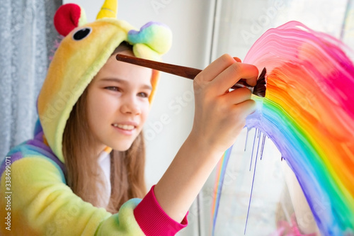 brush. teen girl in kigurumi draws rainbow window photo