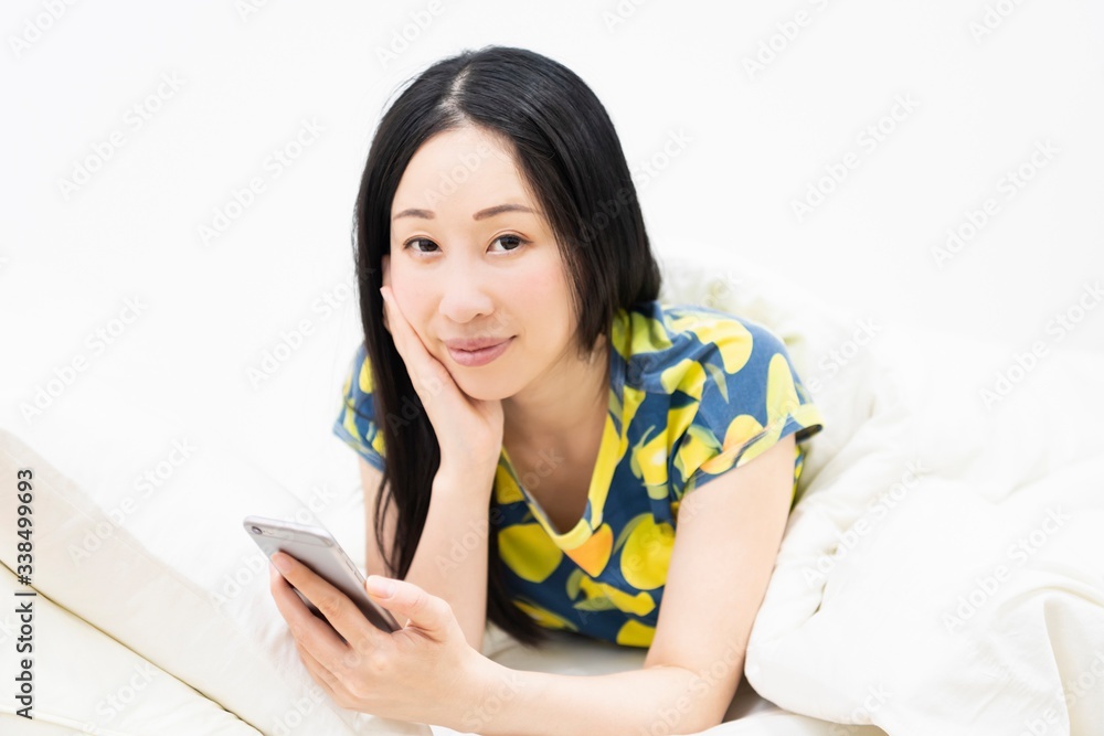 ベッドでスマホを操作する女性 ベッドでスマホを操作する女性