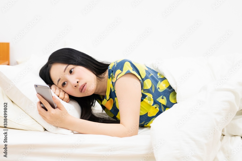 ベッドでスマホを操作する女性 ベッドでスマホを操作する女性