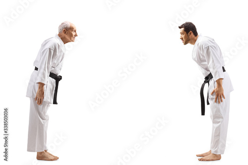 Young man and elderly man in karate kimonos bowing