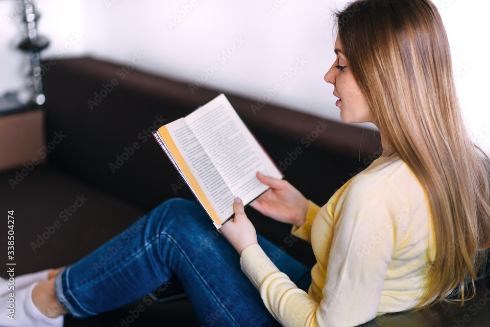 Obraz premium woman lying on sofa and reading book at home