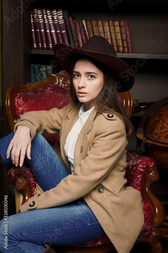 Attractive young woman in fashionable coat and hat sitting in vintage armchair © smmartynenko