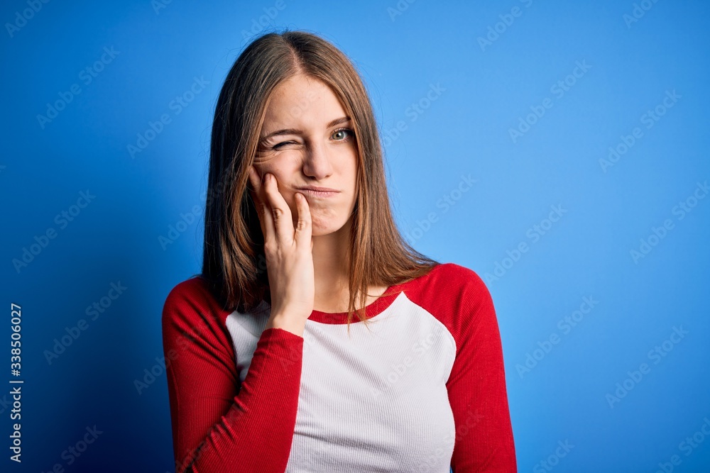 Young beautiful redhead woman wearing casual t-shirt over isolated blue background thinking looking tired and bored with depression problems with crossed arms. Young beautiful redhead woman wearing casual t-shirt over isolated blue background thinking looking tired and bored with depression problems with crossed arms.