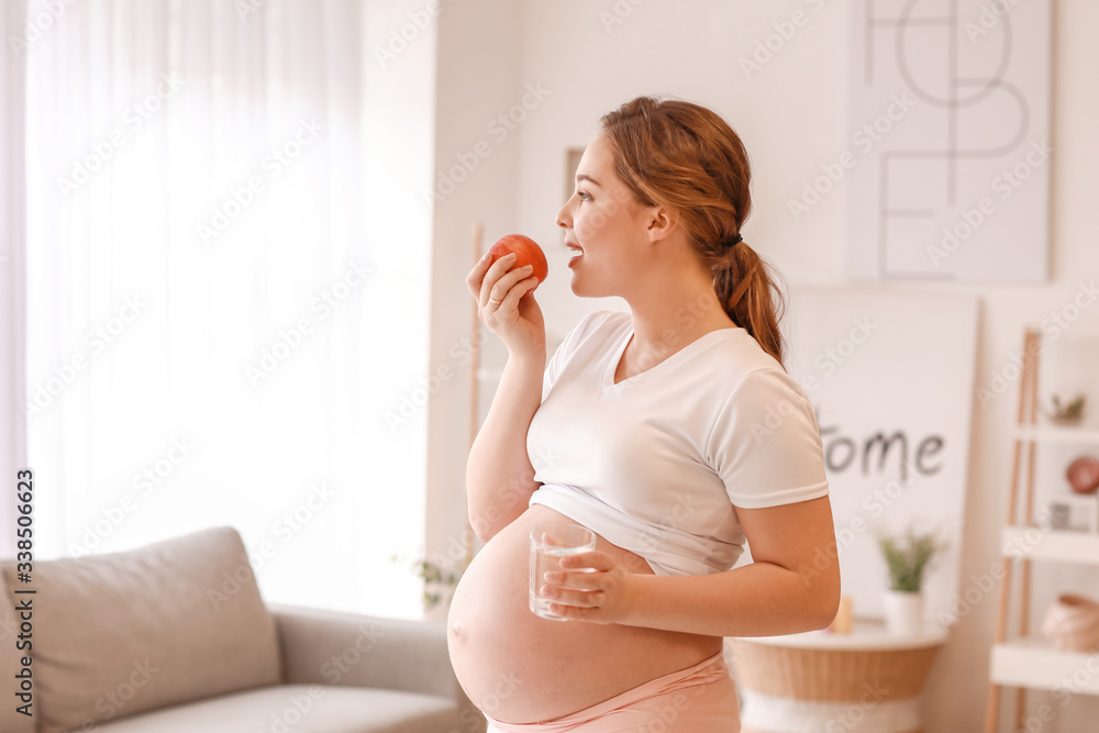 Beautiful pregnant woman with water and apple at home Beautiful pregnant woman with water and apple at home