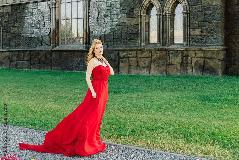 A woman in a red dress stands on a background of a medieval castle A woman in a red dress stands on a background of a medieval castle
