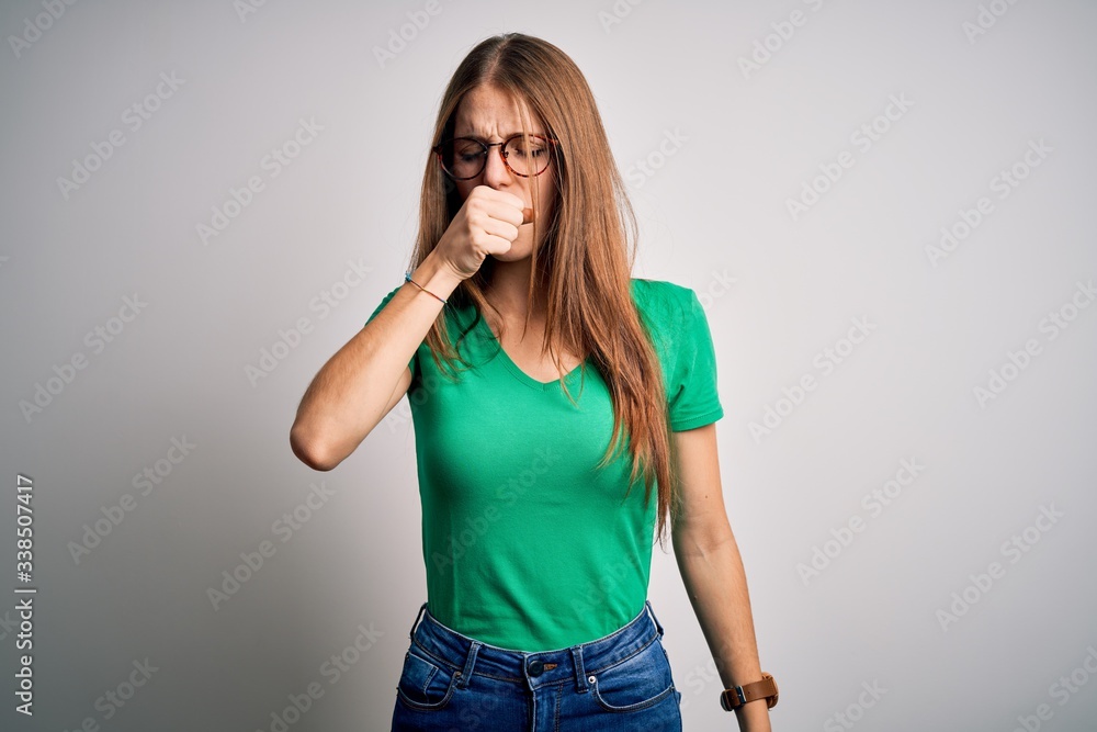 Young beautiful redhead woman wearing casual green t-shirt and glasses over white background feeling unwell and coughing as symptom for cold or bronchitis. Health care concept. Young beautiful redhead woman wearing casual green t-shirt and glasses over white background feeling unwell and coughing as symptom for cold or bronchitis. Health care concept.