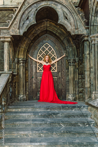 A woman in a red dress stands on a background of a medieval castle