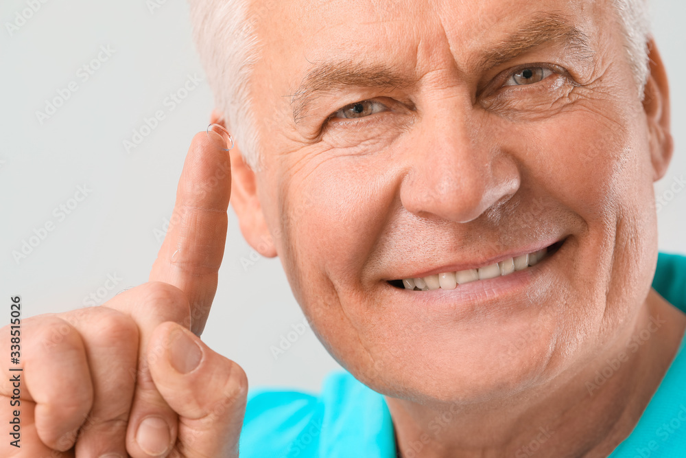 Mature man with contact lens against light background Mature man with contact lens against light background