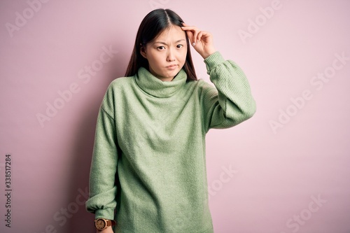 Young beautiful asian woman wearing green winter sweater over pink solated background worried and stressed about a problem with hand on forehead, nervous and anxious for crisis © Krakenimages.com