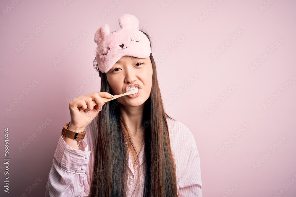 Young beautiful asian woman wearing pajama brushing her teeth using tooth brush and oral paste, cleaning teeth and tongue as healthy health care morning routine Young beautiful asian woman wearing pajama brushing her teeth using tooth brush and oral paste, cleaning teeth and tongue as healthy health care morning routine