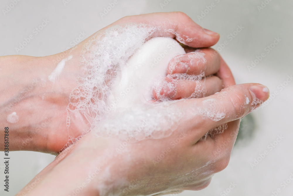 Fototapeta premium Woman uses soap and washes her hands under a faucet. Hygiene and hand cleaning. Prevention and control of coronavirus.