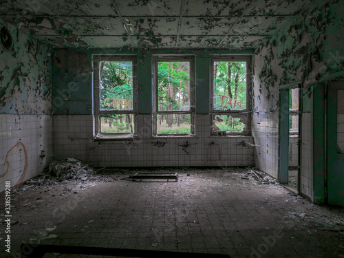 Canvas Print An empty, derelict room with broken windows, looking out on a green forest