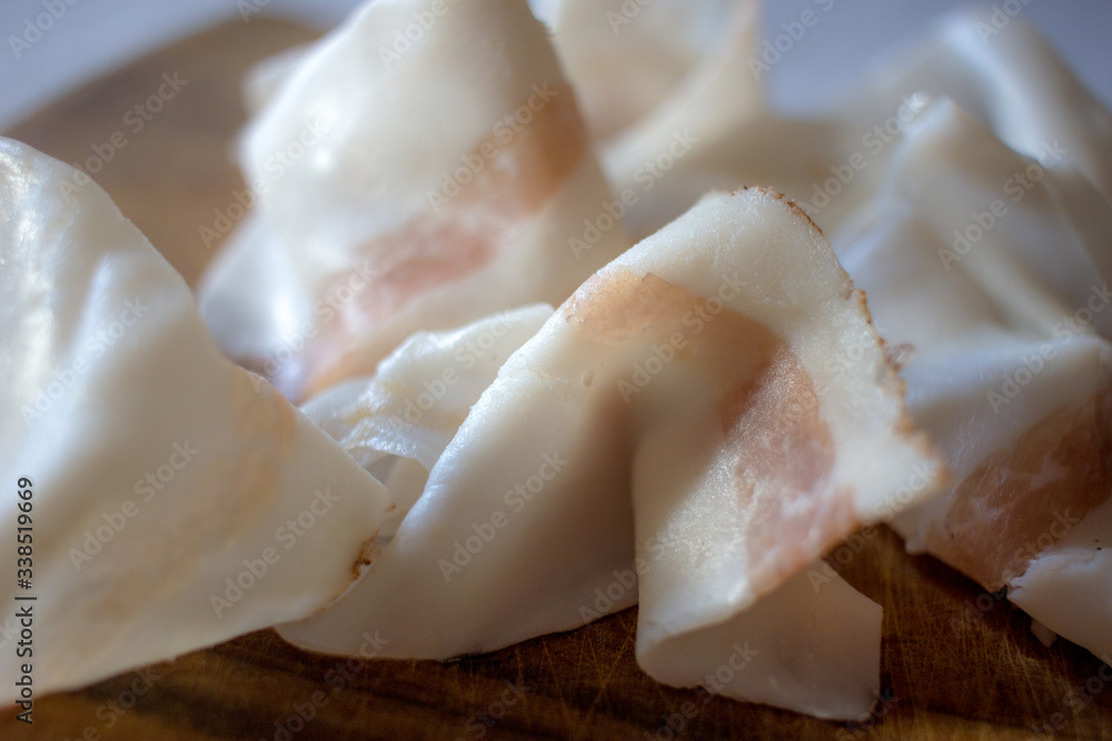 Italian Colonnata lard thinly sliced and laid on a wooden tray. Italian Colonnata lard thinly sliced and laid on a wooden tray.