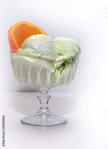 Portion ice cream mint, pistachio in a glass vase and ripe orange