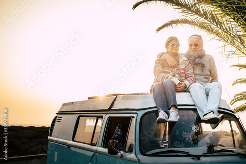 Couple of old senior traveler sit down  together on the roof of the van enjoy the sunset time together with love - forever and vacation concept for traveler retired people #338519808