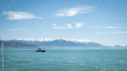 Boat on the ocean with mountain backdrop. Shot in Kaikoura peninsula, New Zealand photo