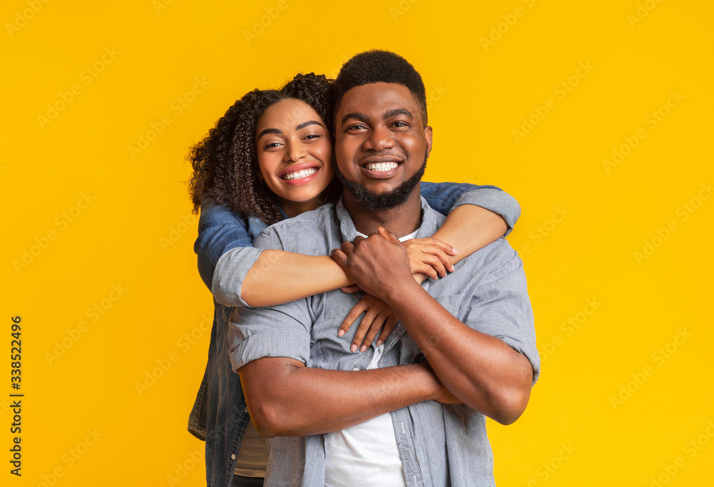 Obraz premium Portrait of black couple in love hugging and smiling at camera