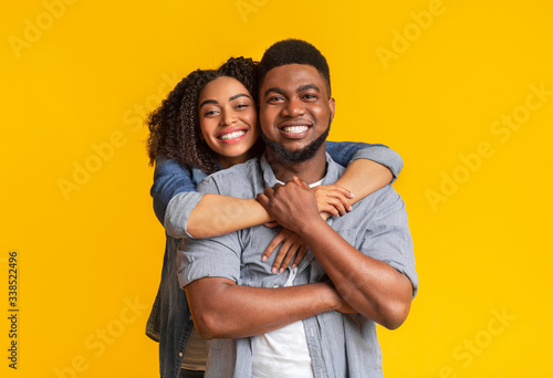 Portrait of black couple in love hugging and smiling at camera