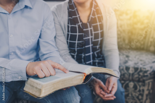 Close up of young man hands holding and point on bible page while reading and study bible with his friends at home, Christian background with copy space