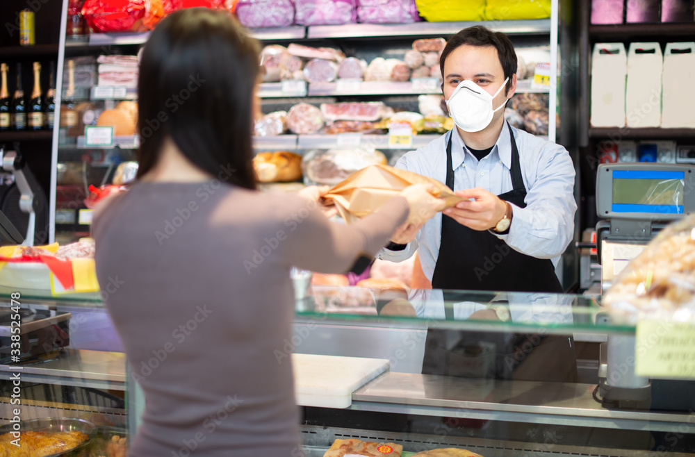 Shopkeeper serving a customer while wearing a mask