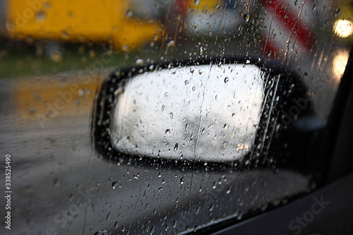 car mirror behind the glass with rain drops