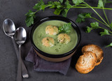 Cream-soup greens with croutons in a bowl on a dark gray background top view