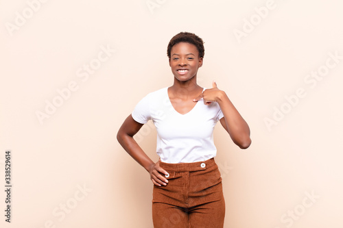 young pretty black womanlooking happy, proud and surprised, cheerfully pointing to self, feeling confident and lofty photo