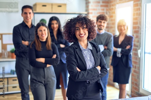 Group of business workers smiling happy and confident. Posing together with smile on face looking at the camera, young beautiful woman with crossed arms at the office