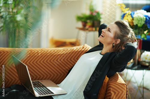 relaxed stylish middle age woman with laptop laying on sofa