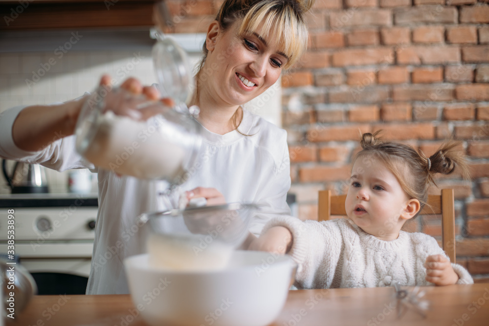 Mother and daughter baking cookies in their kitchen. Quarantine stay at home family activities for kids. Mother and daughter baking cookies in their kitchen. Quarantine stay at home family activities for kids.