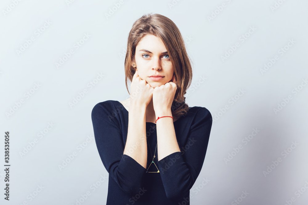 portrait of beautiful young brunette girl holding hand on chin isolated on gray background portrait of beautiful young brunette girl holding hand on chin isolated on gray background