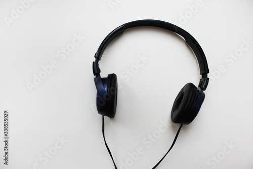 Black on-ear headphones isolated on white empty table background. Old music listening technology accessory, simple noise cancelling headphones close up top view with blank copy space