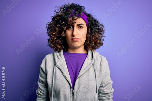 Beautiful curly arab sportswoman doing sport wearing sportswear over purple background skeptic and nervous, frowning upset because of problem. Negative person.