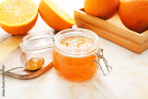 Jar of orange jam on white table