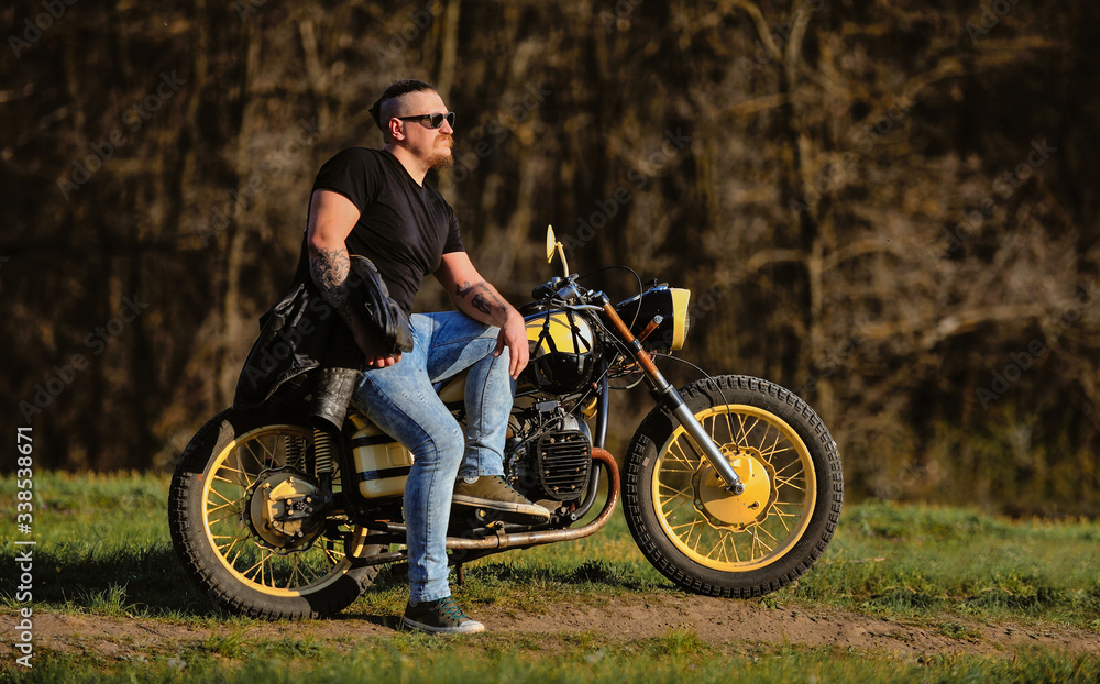 Fototapeta premium Biker leaning on a motorcycle enjoying the view