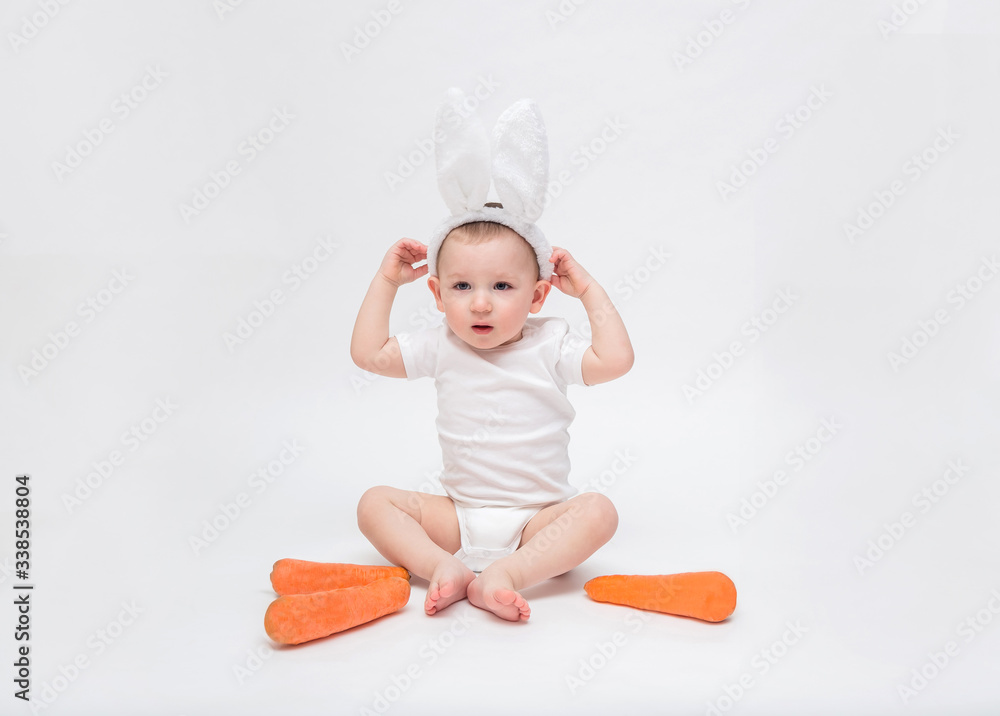 baby boy on a white background in a white bodysuit. A small boy with Bunny ears and a carrot baby boy on a white background in a white bodysuit. A small boy with Bunny ears and a carrot