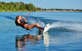 Beautiful girl wakeboarding on the shore of the river sea in the summer on a spring day in a jacket
