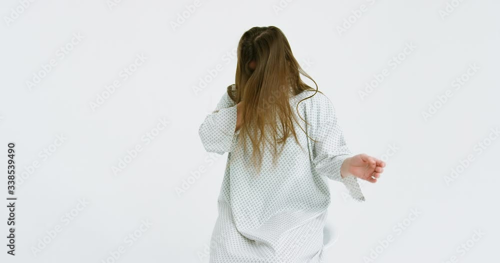 Camera zooming in at young Caucasian beautiful ill woman in hospital night dress sneezing and covering face with hand. Unhealthy female medical patient with flu or cold. Virus symptoms. Camera zooming in at young Caucasian beautiful ill woman in hospital night dress sneezing and covering face with hand. Unhealthy female medical patient with flu or cold. Virus symptoms.