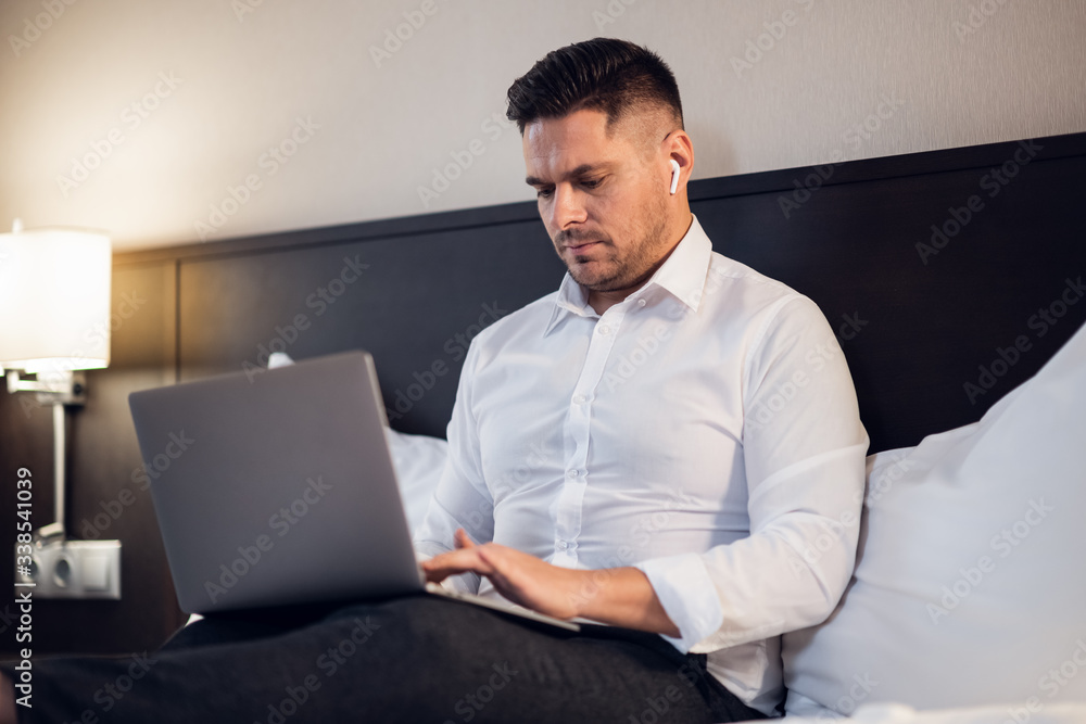Relaxed Businessman on his laptop in bed Relaxed Businessman on his laptop in bed