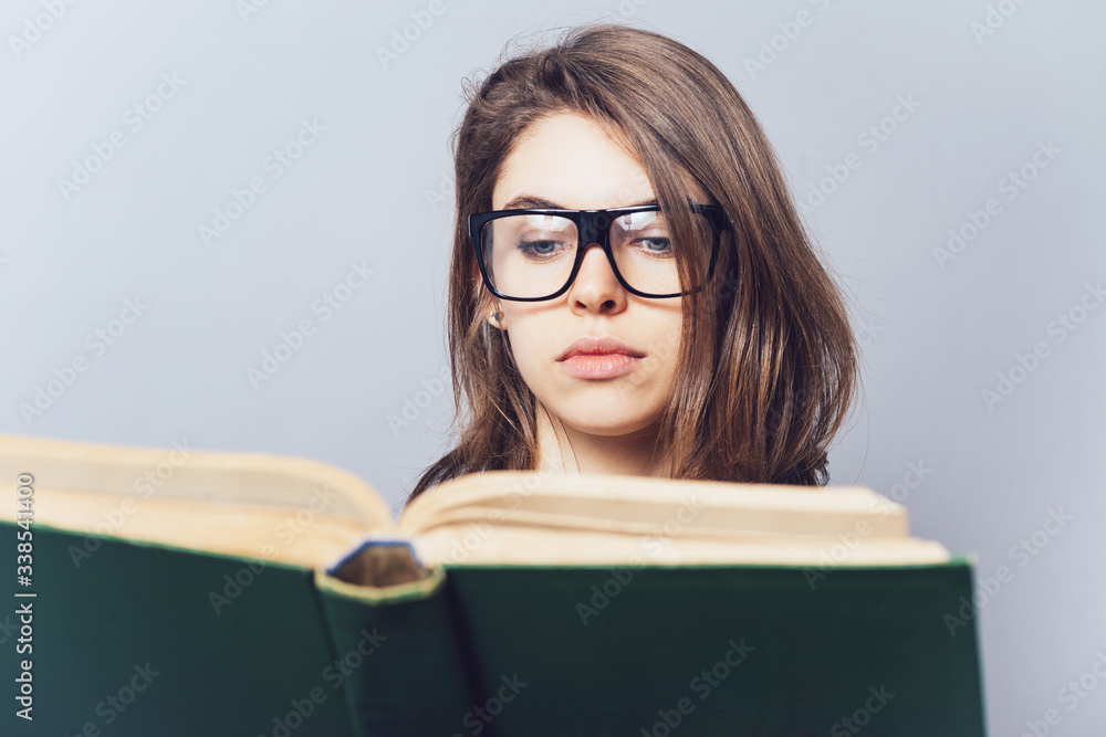 girl with glasses reading a book, looking from her girl with glasses reading a book, looking from her