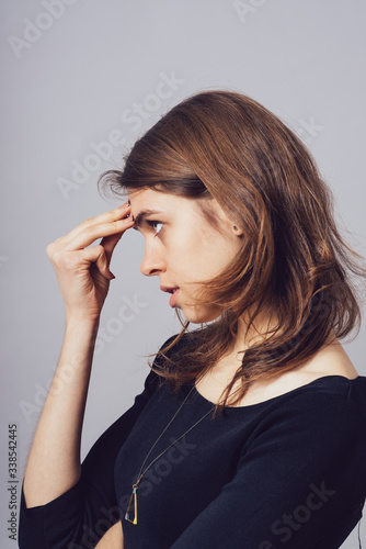 Woman thinking with his hand on his forehead. profile
