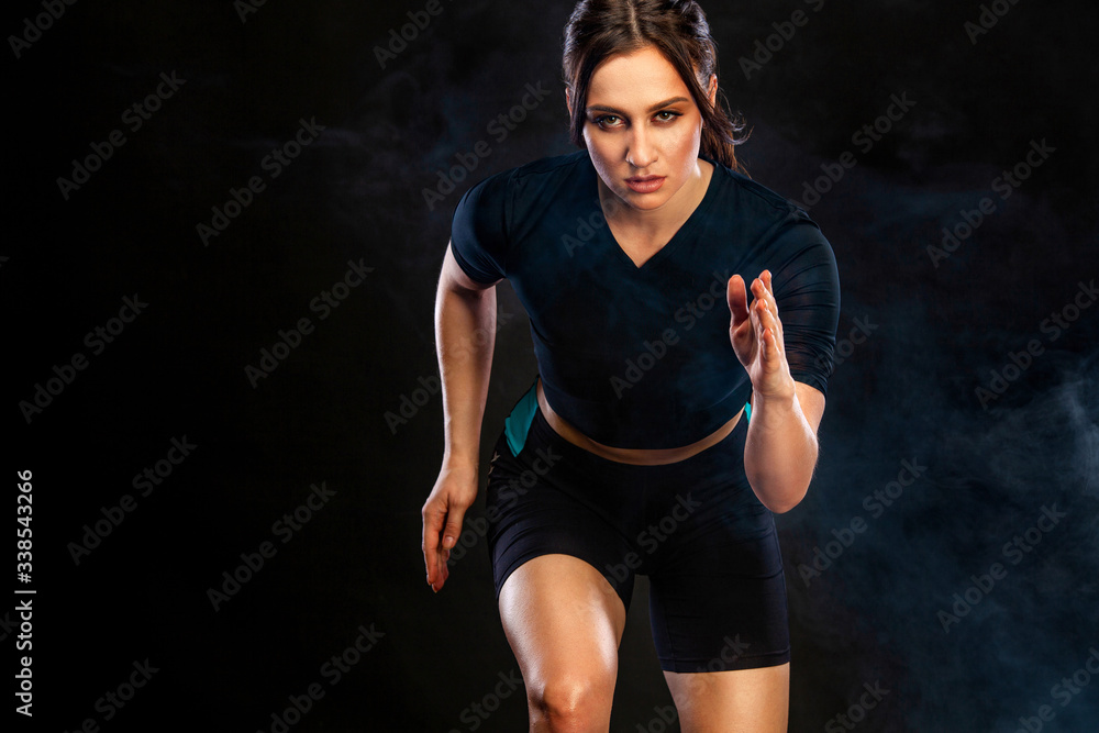 Fototapeta premium Sprinter and runner girl. Running concept. Woman running on the black background. The concept of a healthy lifestyle and sport. Woman in sportswear.