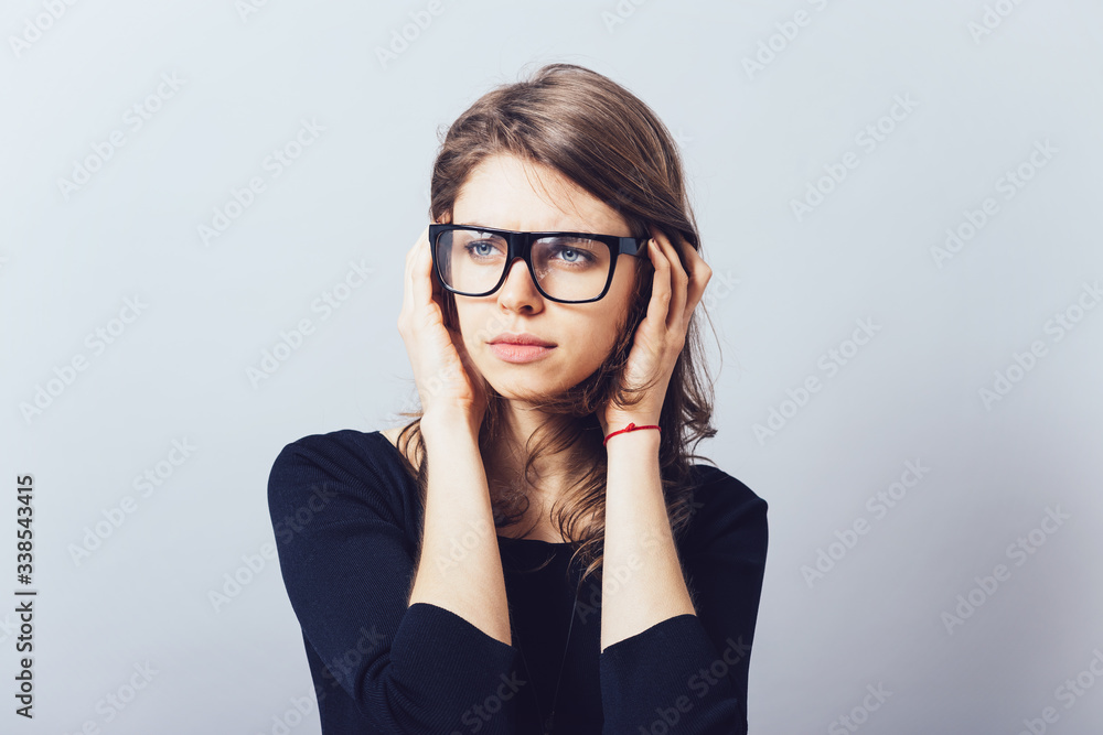 Woman in glasses, adjusts his glasses or hair on a grey background