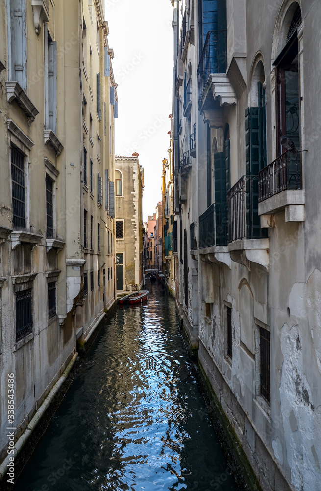 Old narrow canal with parked boats quiet streets of Venice at summer morning. Traveling concept background, Italy