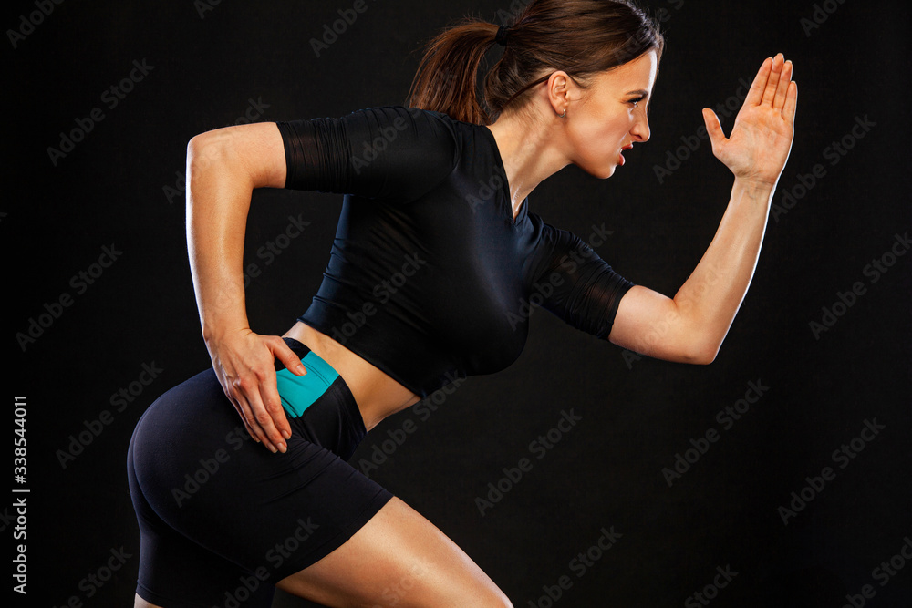 Obraz premium Sprinter and runner girl. Running concept. Woman running on the black background. The concept of a healthy lifestyle and sport. Woman in sportswear.